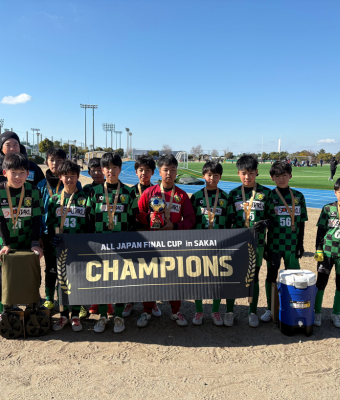 サッカー全国大会で優勝した少年たちと表彰バナー